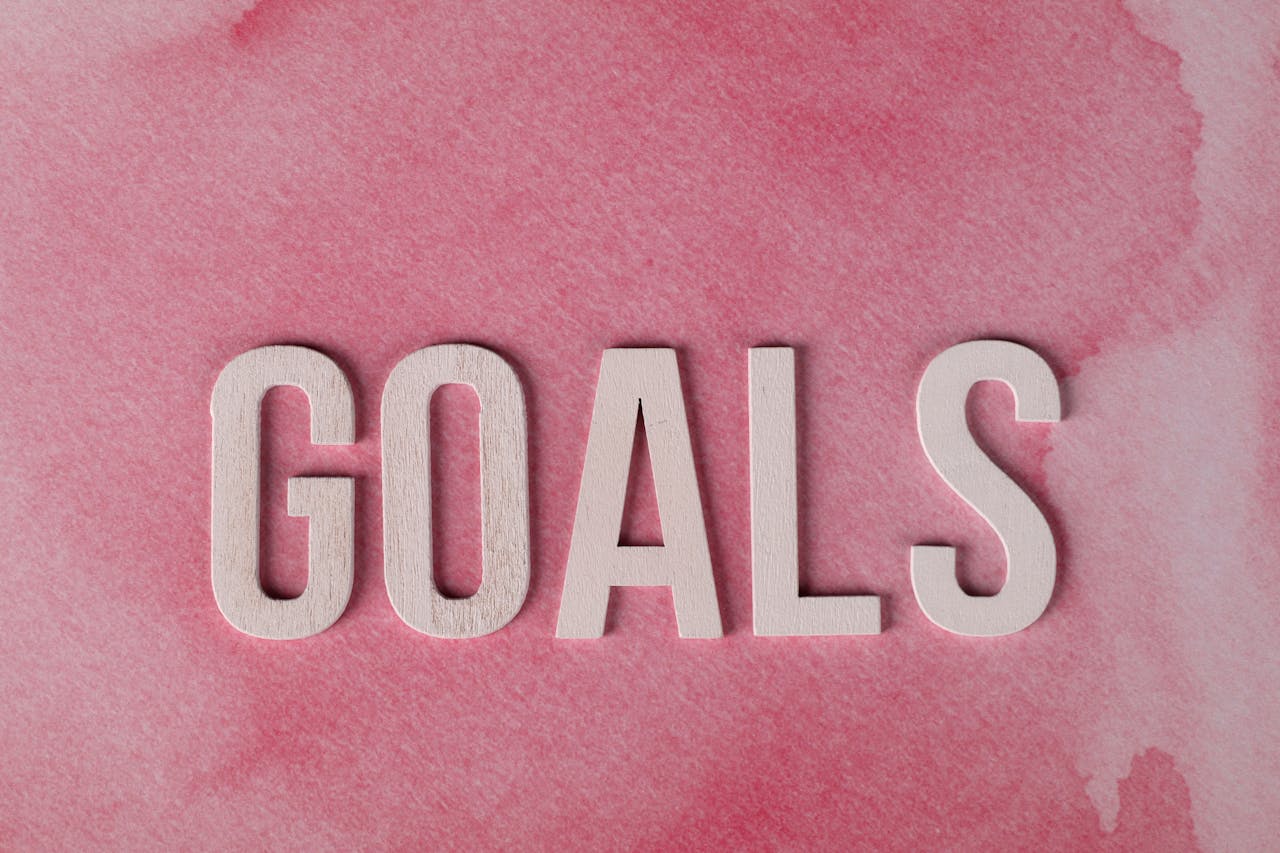 about-us Motivational word 'GOALS' on a pink watercolor background for inspiration.
