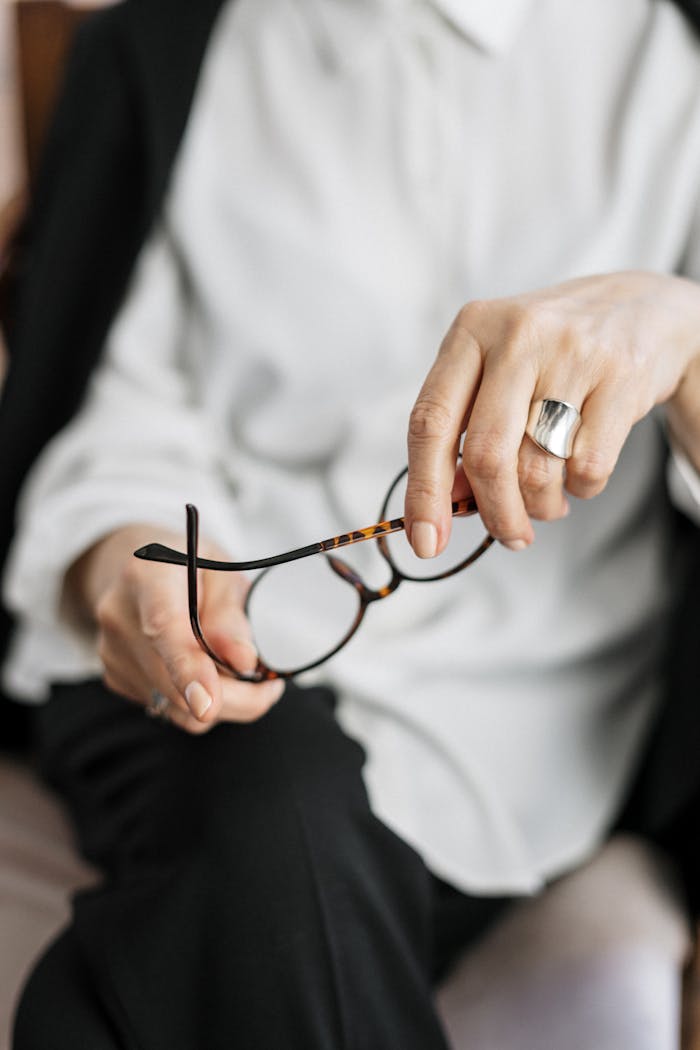 about-us Close-up of a woman holding glasses, symbolizing thought and professionalism.