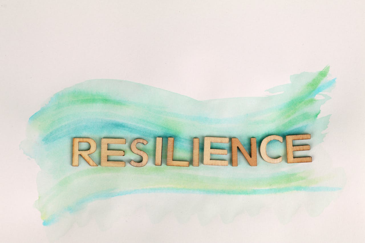 who-we-are The word 'Resilience' painted with green watercolor and wooden letters on a white background.