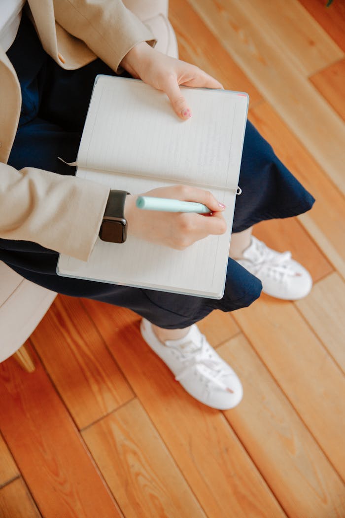 High-angle view of an adult writing notes in a notebook during a therapy session.